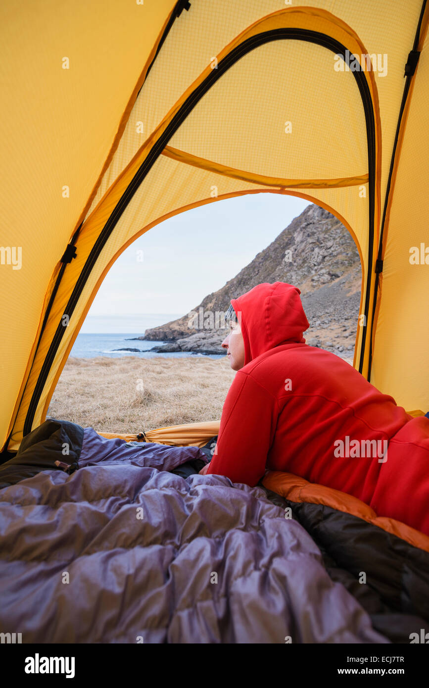 Female backpacker looks out of tent while wild camping at Horseid beach, Moskenesøy, Lofoten Islands, Norway Stock Photo