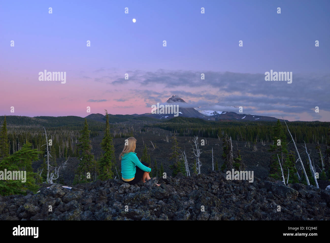 Woman sitting along McKenzie Pass with North Sister volcano in the back,Oregon,USA Stock Photo
