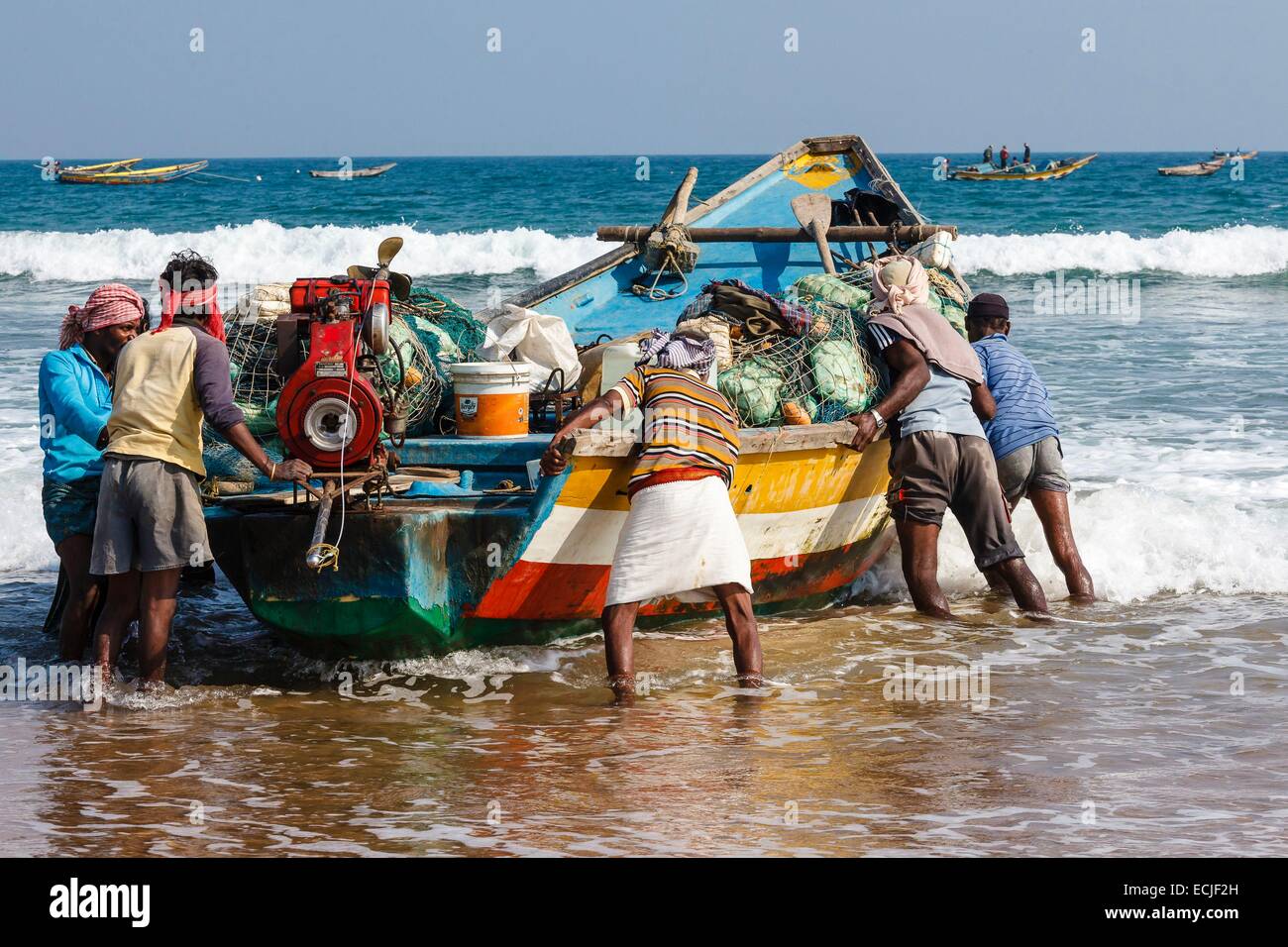 India, Odisha, Gopalpur, fishermen pushing their boat to the sea Stock Photo