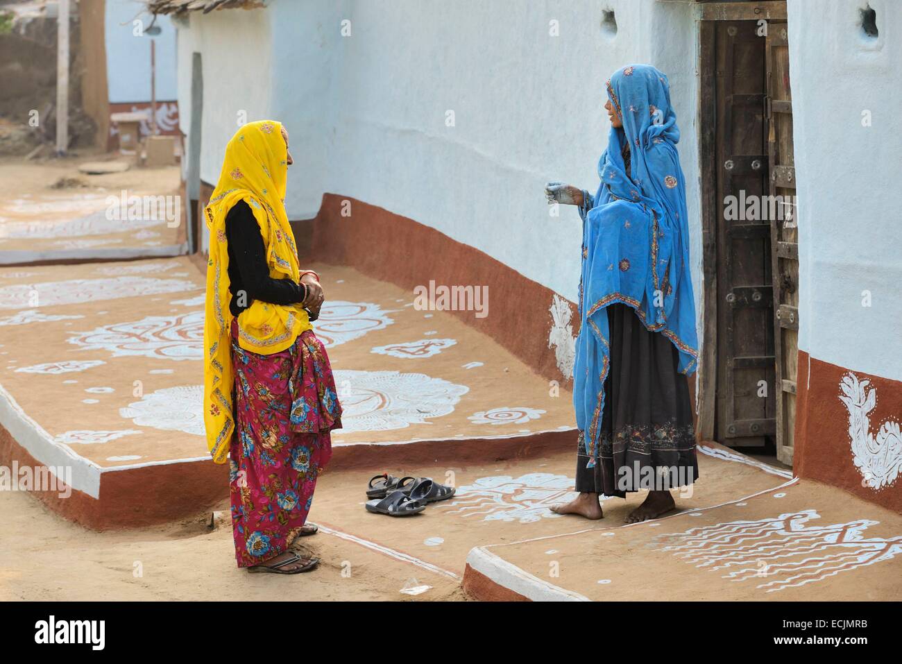 India, Rajasthan, Tonk region, Women chatting The paintings on the ground are meant to welcome goddess Lakshmi and ward off evil spirits Stock Photo