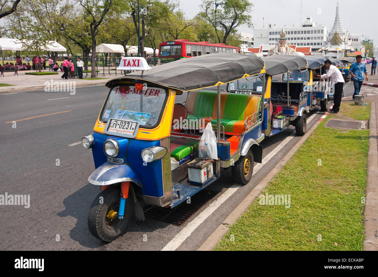 Horizontal streetscape view of a row of tuk-tuks parked up along the road in Bangkok. Stock Photo