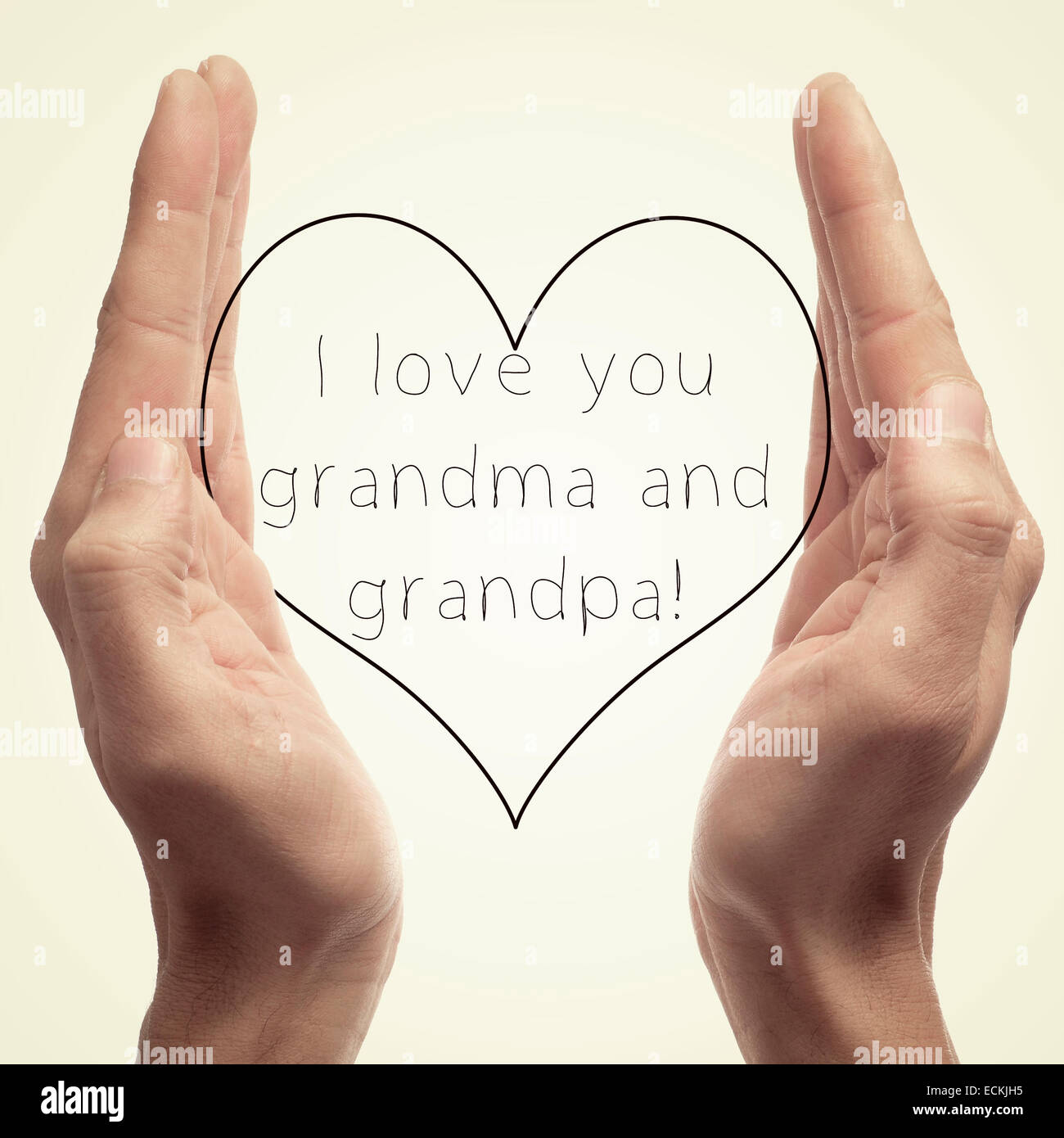someone holding a drawn heart in his hands and the sentence I love you grandma and grandpa written in it Stock Photo