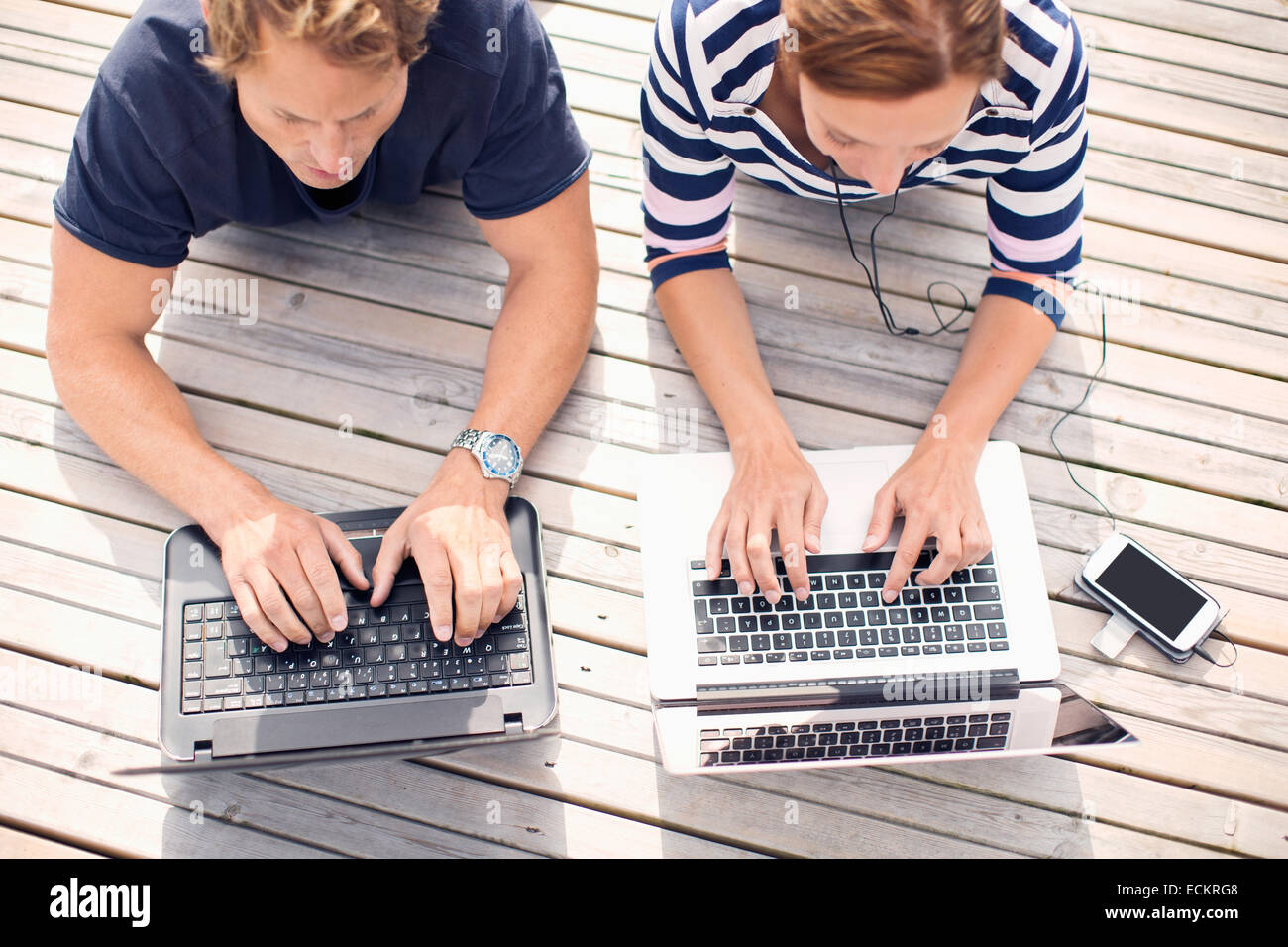 High angle view of mature couple using laptops while lying on pier Stock Photo