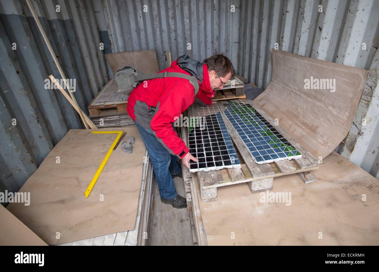 Erfurt, Germany. 15th Dec, 2014. Art restorer Peter Jung examines segments of a wall mosaic titled 'Die Beziehung des Menschen zu Natur und Technik' (the relationship between humans to nature and technology) by Spanish artist Josep Renau in a container in Erfurt, Germany, 15 December 2014. The restoration work of the mosaic, which was threatened by the demolition of the cutlure and leisure centre 'Moskauer Platz' in Erfurt, is expected to amount to 400,000 euro. Photo: Michael Reichel/dpa/Alamy Live News Stock Photo