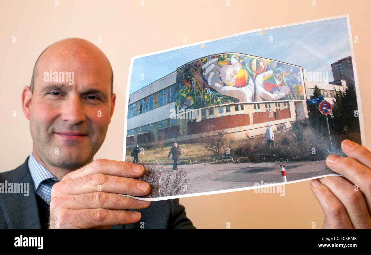Erfurt, Germany. 15th Dec, 2014. Philip Kurz of the Wuestenrot foundation shows a historic picture of the mosaic titled 'Die Beziehung des Menschen zu Natur und Technik' (the relationship between humans to nature and technology) by Spanish artist Josep Renau attached to a building in Erfurt, Germany, 15 December 2014. The restoration work of the mosaic, which was threatened by the demolition of the cutlure and leisure centre 'Moskauer Platz' in Erfurt, is expected to amount to 400,000 euro. Photo: Michael Reichel/dpa/Alamy Live News Stock Photo