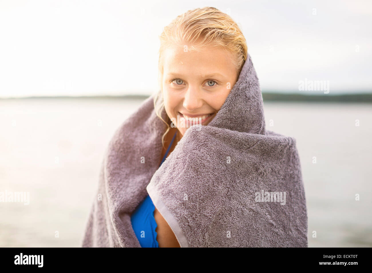 Portrait of smiling woman wrapped in towel against lake Stock Photo - Alamy