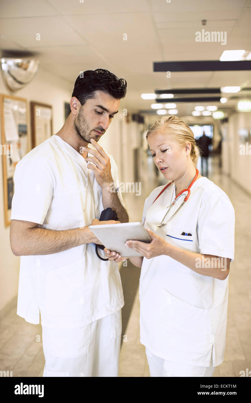 Doctors discussing over digital tablet in hospital corridor Stock Photo