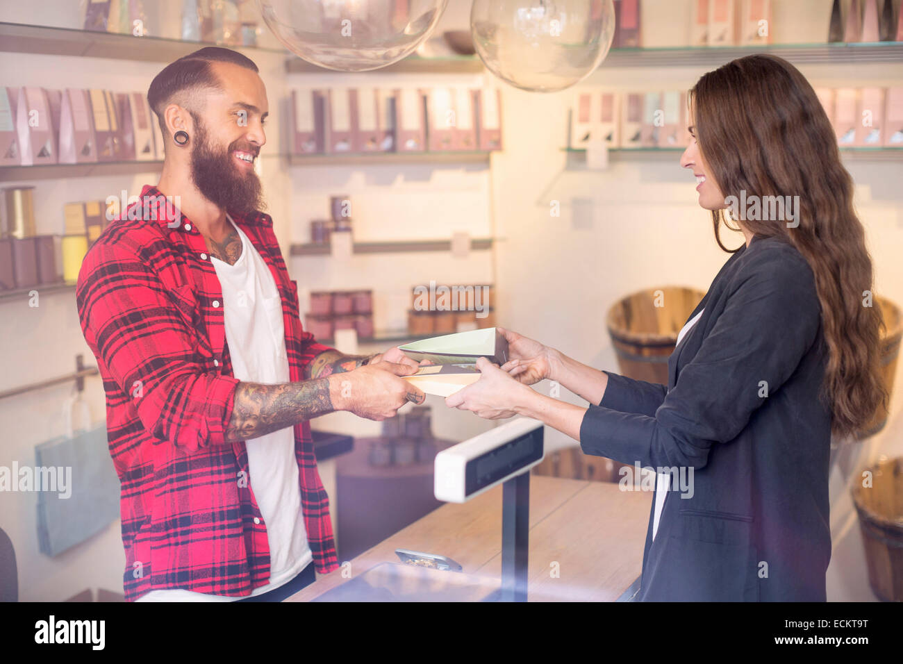 Happy owner giving candies to customer in shop Stock Photo