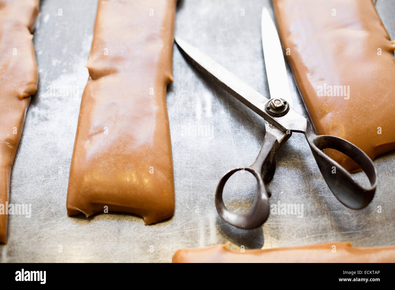 Scissors and caramel on container in candy store Stock Photo