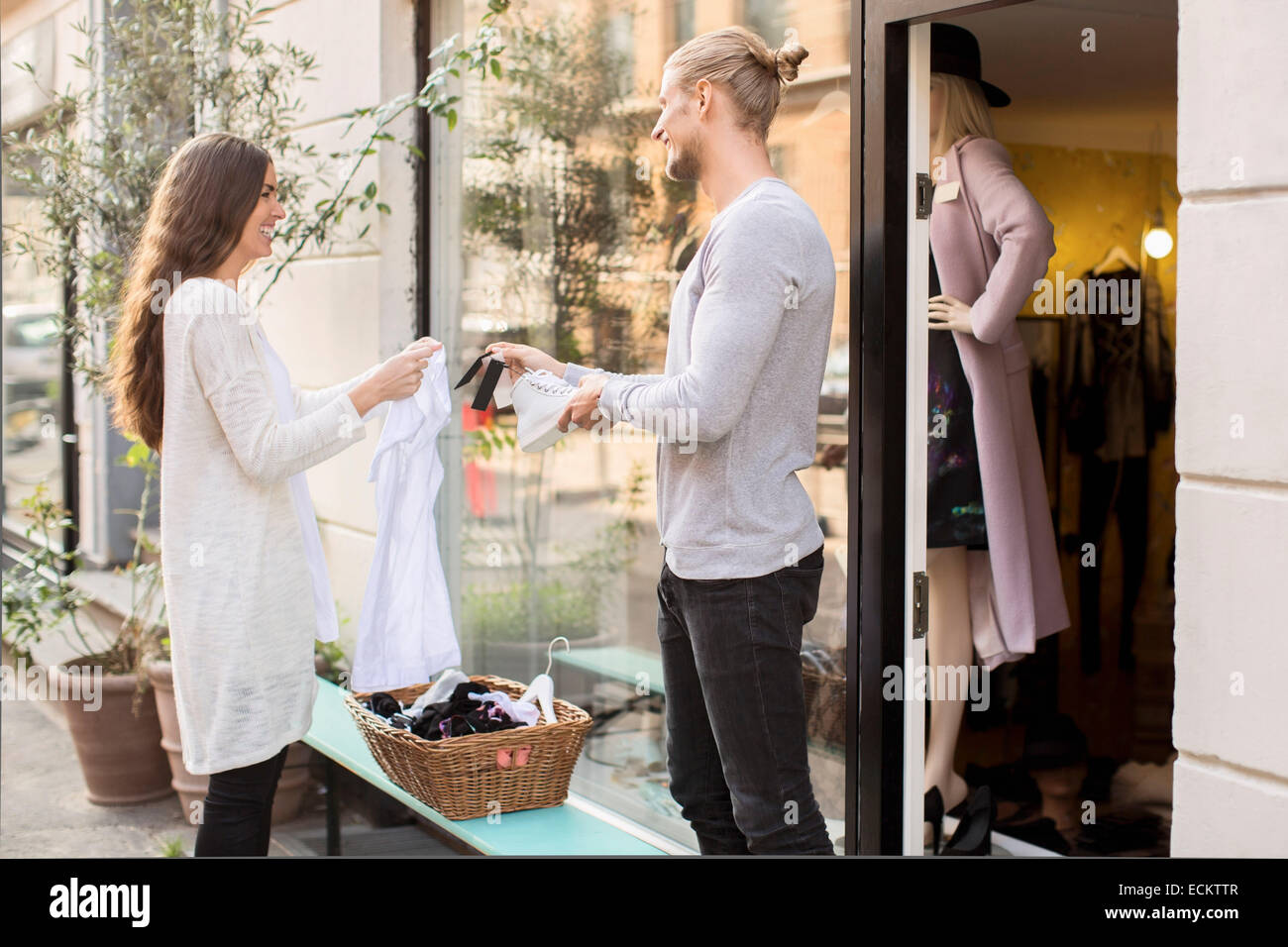 Happy Male owner showing price tag of shoe to customer outside boutique