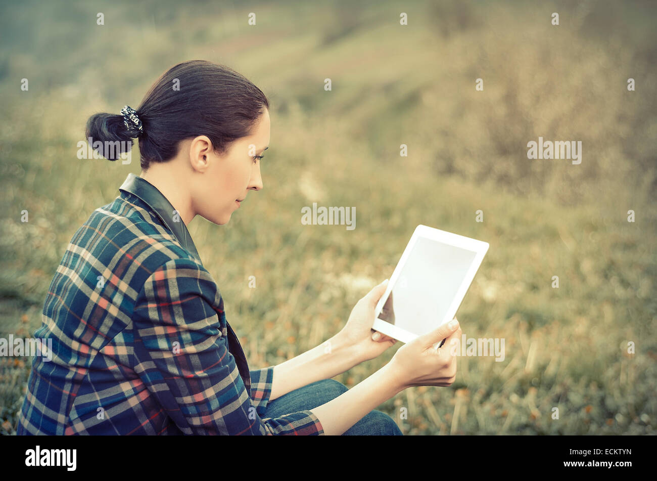 Young woman using tablet outdoor sitting on grass Stock Photo