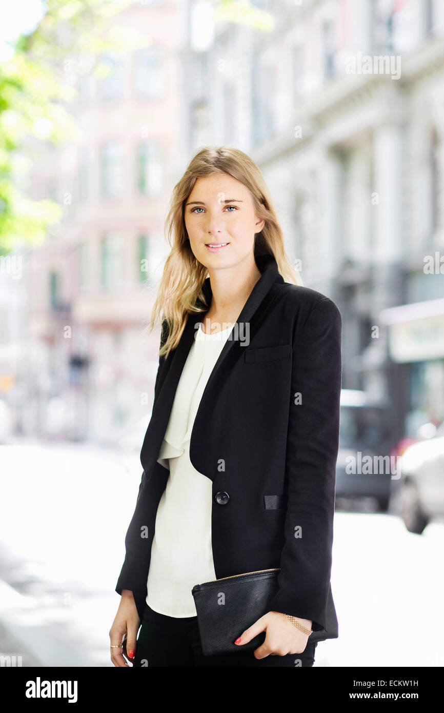 Portrait of young woman standing on city street Stock Photo - Alamy