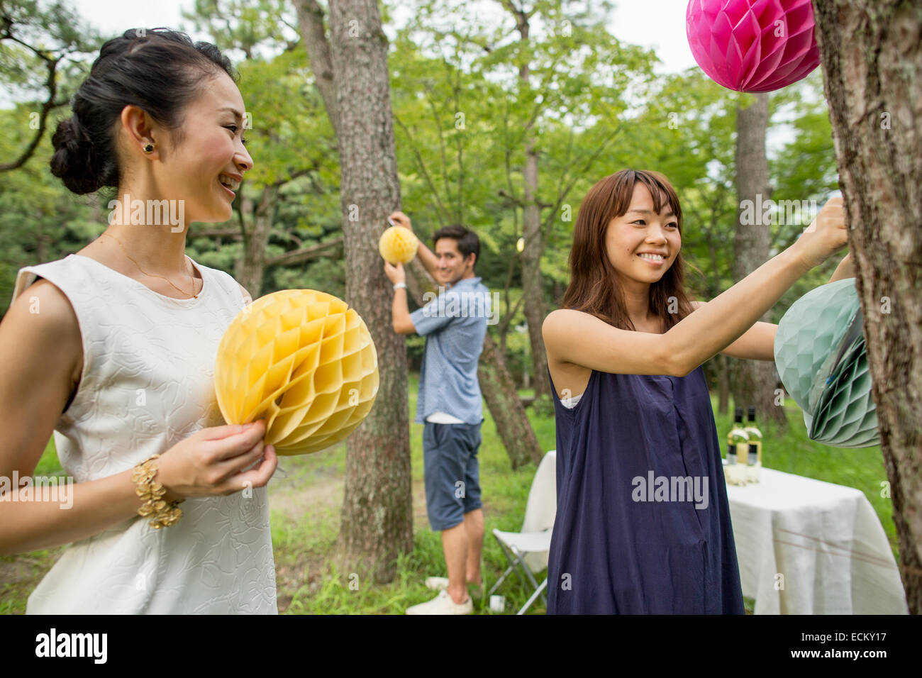 Group of people hanging lanterns and flags on trees in a wood. Stock Photo