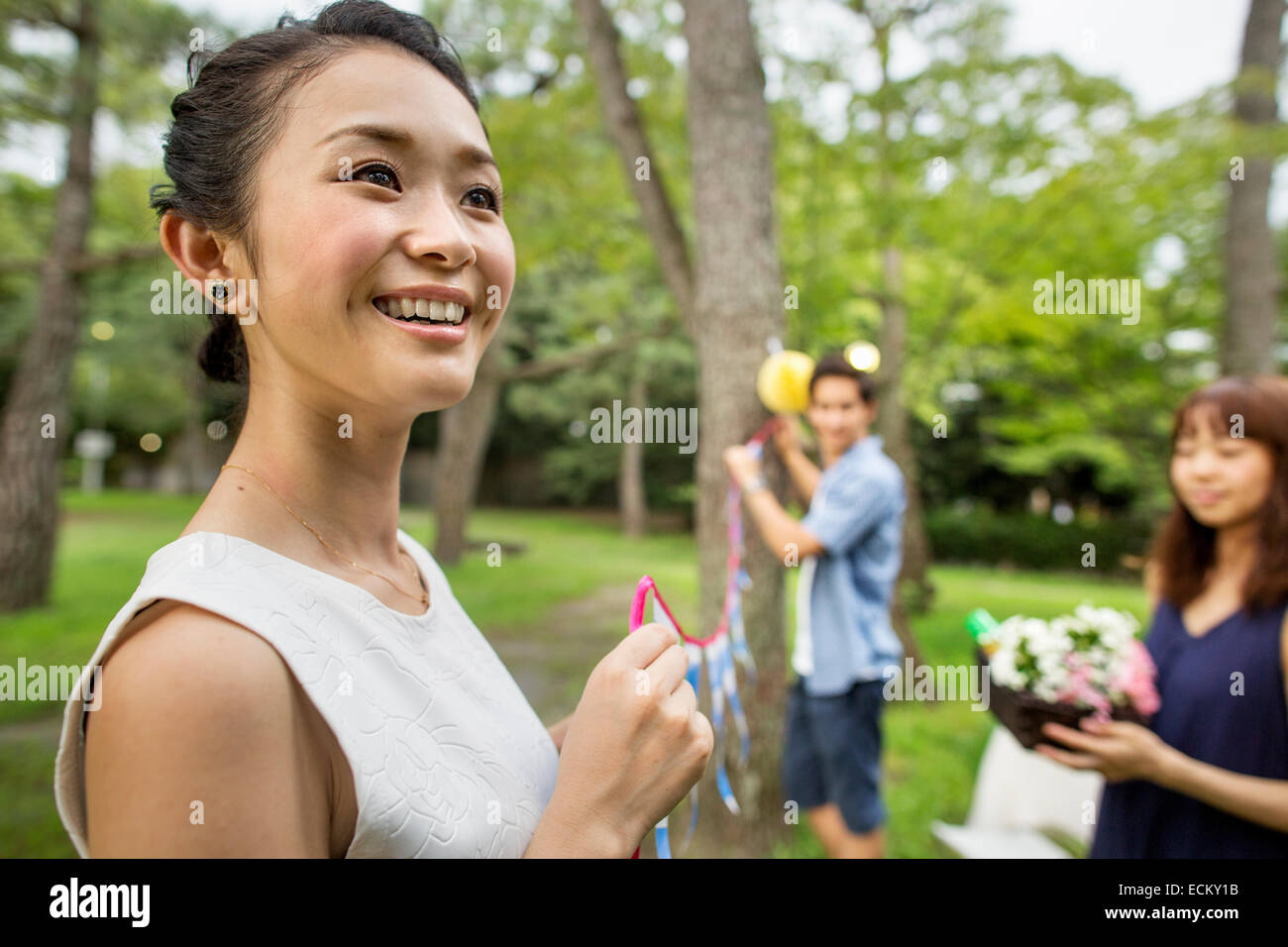 Group of people hanging lanterns and flags on trees in a wood. Stock Photo