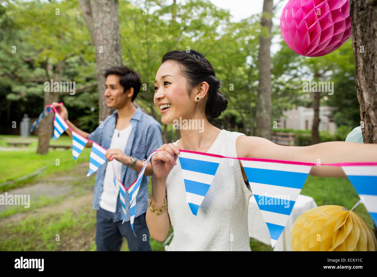 Group of people hanging lanterns and flags on trees in a wood. Stock Photo
