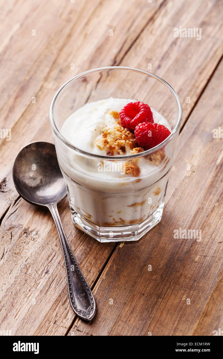 Glass of delicious yogurt muesli with raspberries on wooden background Stock Photo