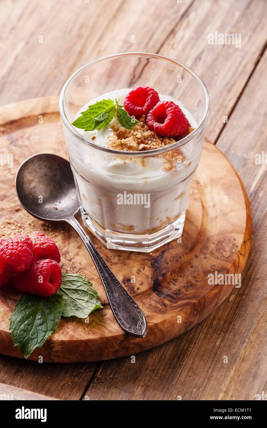 Glass of delicious yogurt muesli with raspberries on wooden background Stock Photo