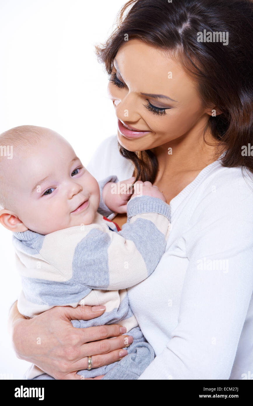 Loving mother cradling her happy baby son in her arms as the infant
