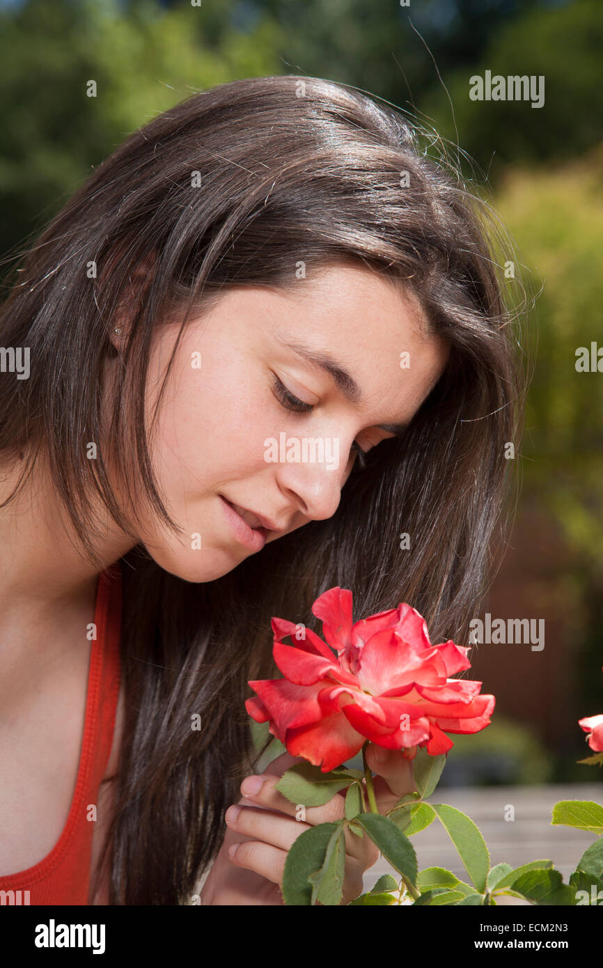 portrait of pretty young woman face smelling red flower Stock Photo - Alamy