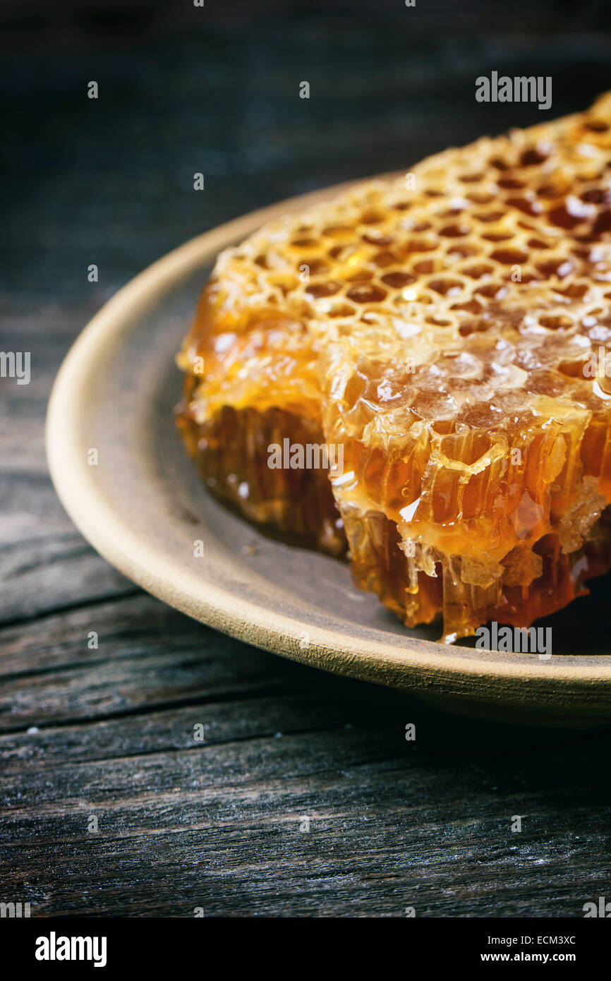Clode up of honeycomb on ceramic plate over old wooden table. Stock Photo