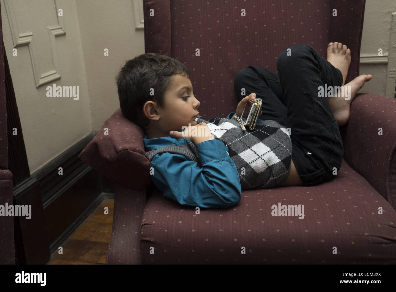 Five year old boy watches a movie on his mom's iphone at home. Stock Photo