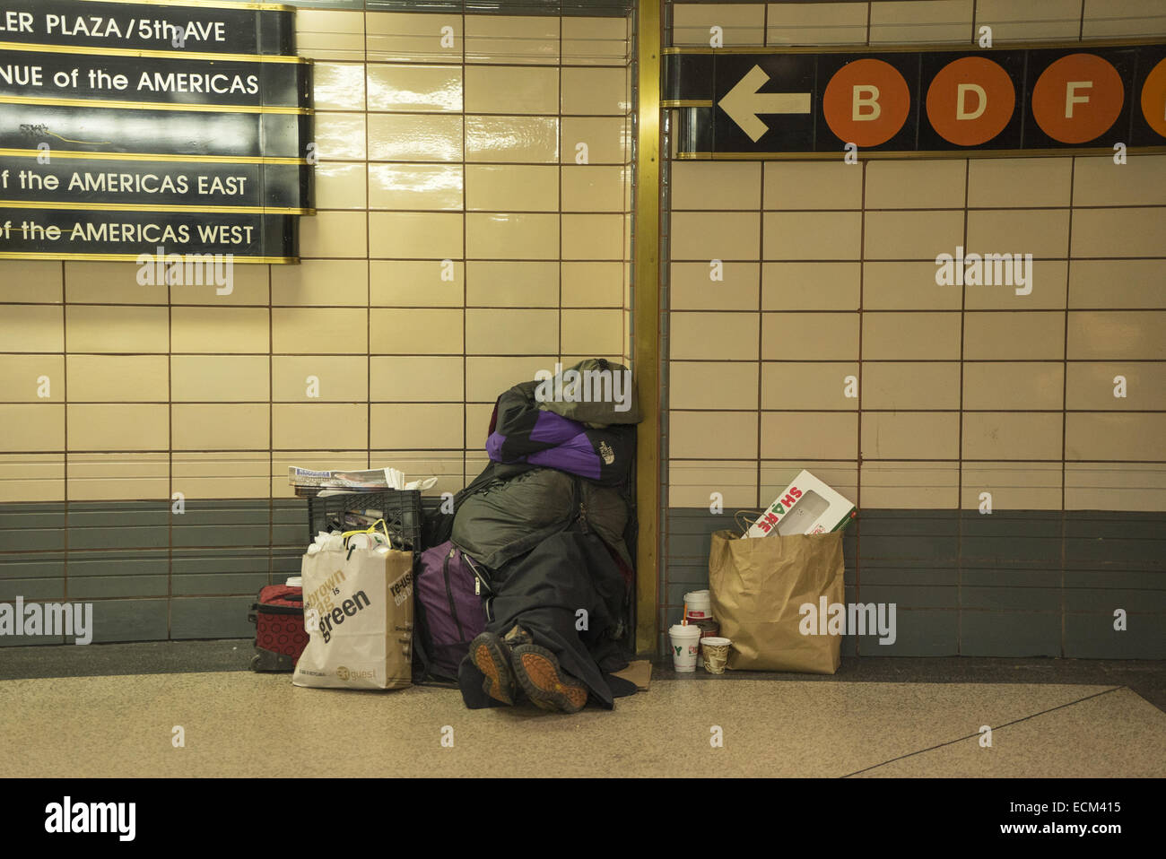 Homeless person takes refuge from the cold in an underground subway station at 34th St. in NYC. Stock Photo