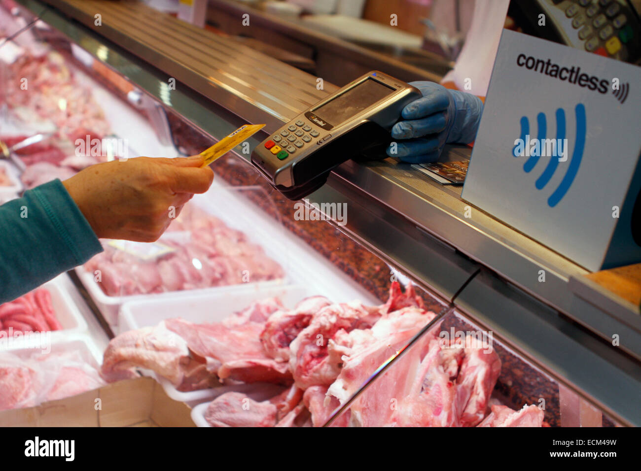 A woman pays on a butchery with a contactless credit card system in the island of Majorca, Spain Stock Photo