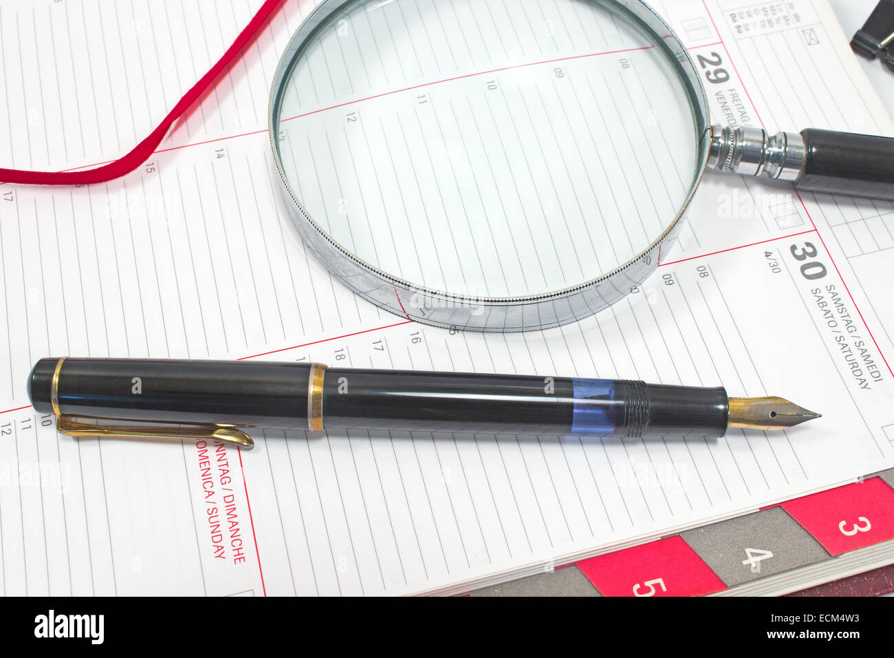 Fountain pen and magnifying glass on personal organizer Stock Photo - Alamy