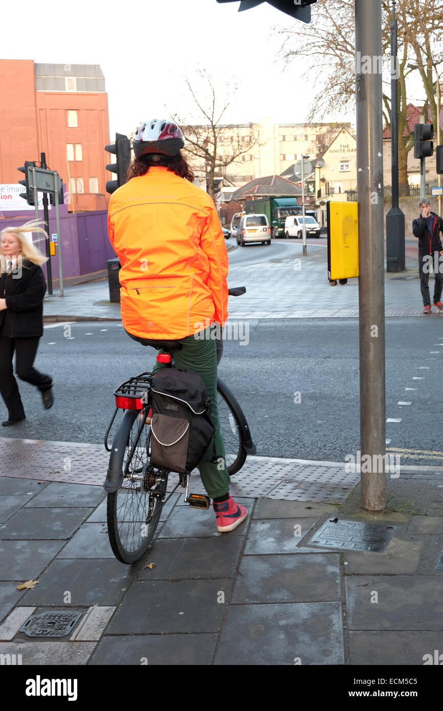 Young woman waiting with her bike at a pedestrian crossing in Bristol. 16th December 2014 Stock Photo