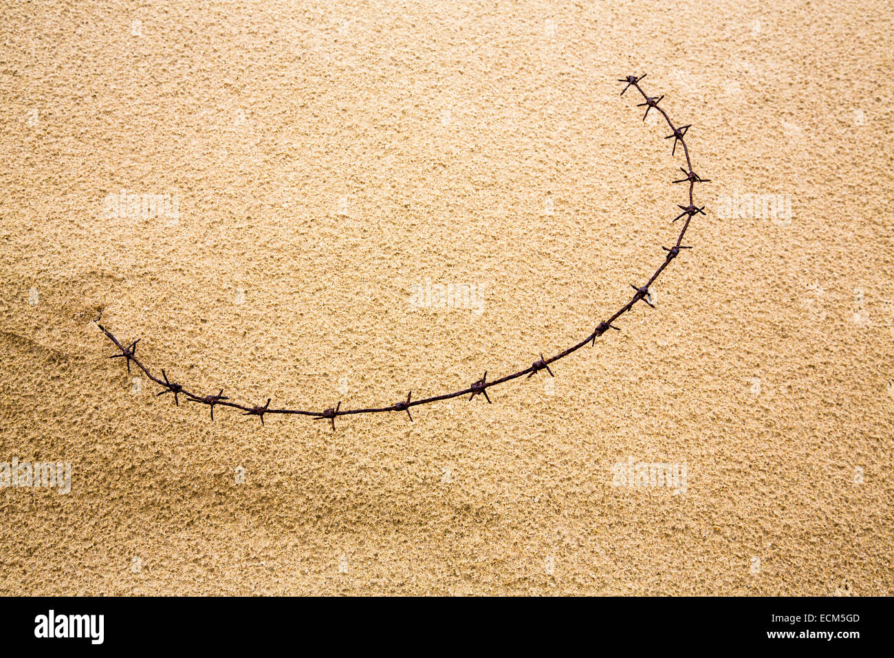 Rusty, old barbed wire on a sandy beach Stock Photo - Alamy