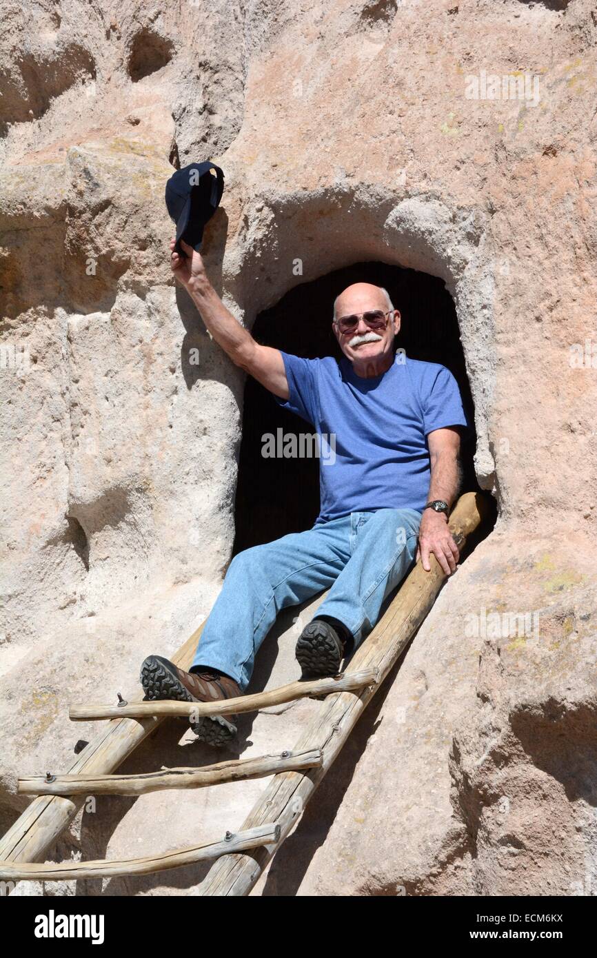 80 year old brother at top of a ladder leading into a room carved out of rock by the Anasazi Indians over 10,000 years ago. Stock Photo