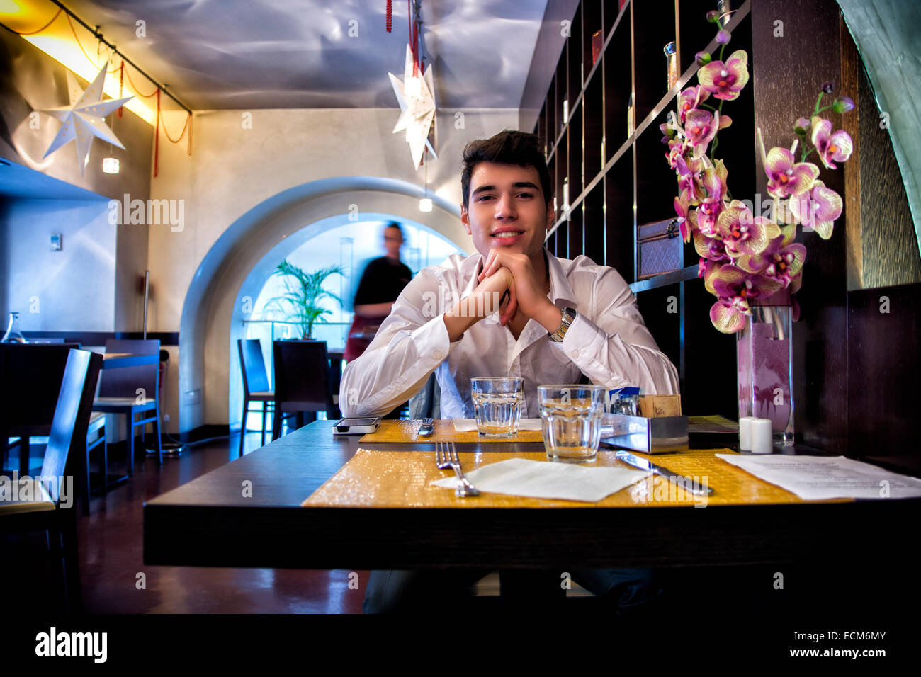 Handsome young man having lunch in elegant restaurant alone smiling and looking at camera Stock Photo
