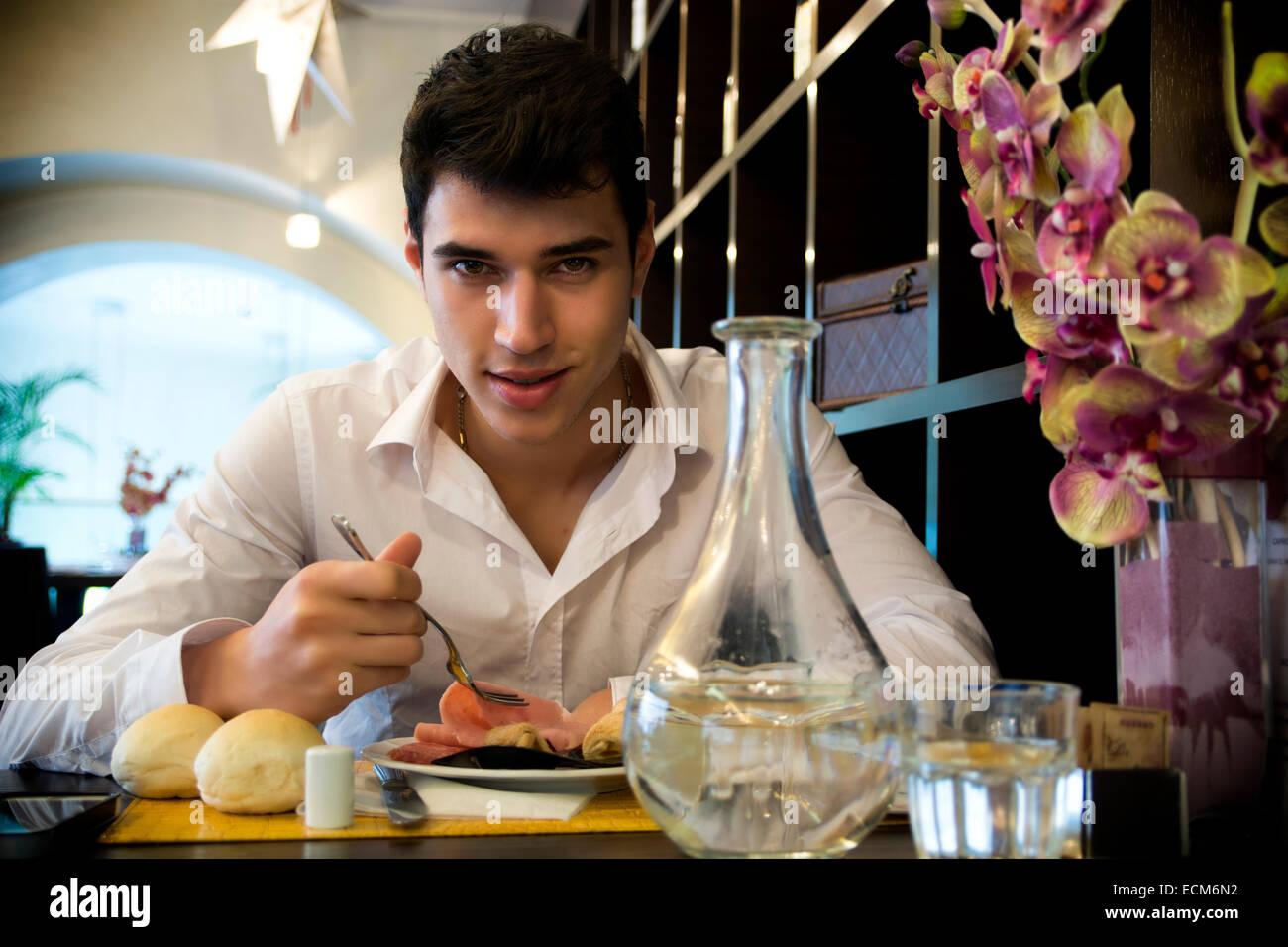 Handsome young man having lunch in elegant restaurant alone smiling and looking at camera Stock Photo