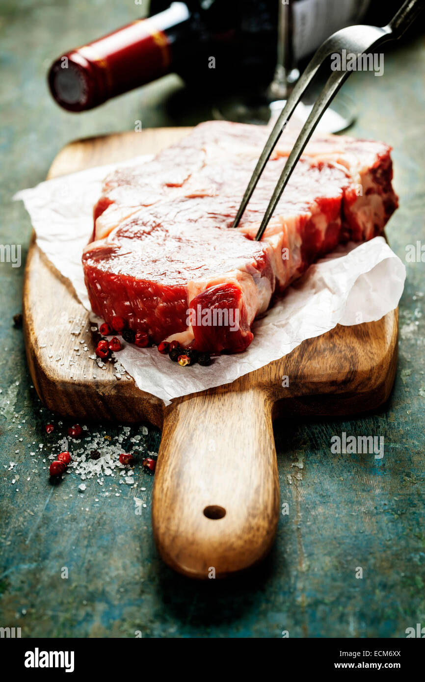 Marbled beef steak with a bottle of wine and wine glass on old wood background Stock Photo