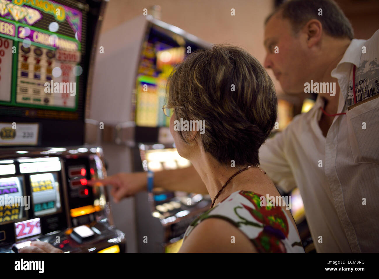 Man explaining readout and rules to a woman on slot machines in a casino Dominican Republic Stock Photo