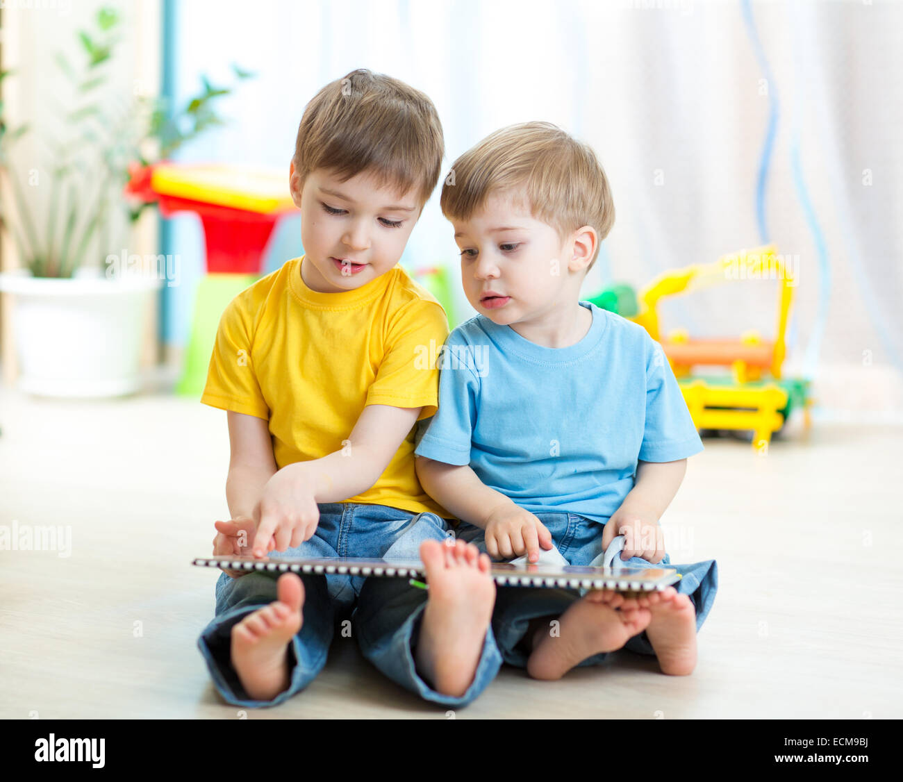 Two boys sitting beside him and read a book Stock Photo