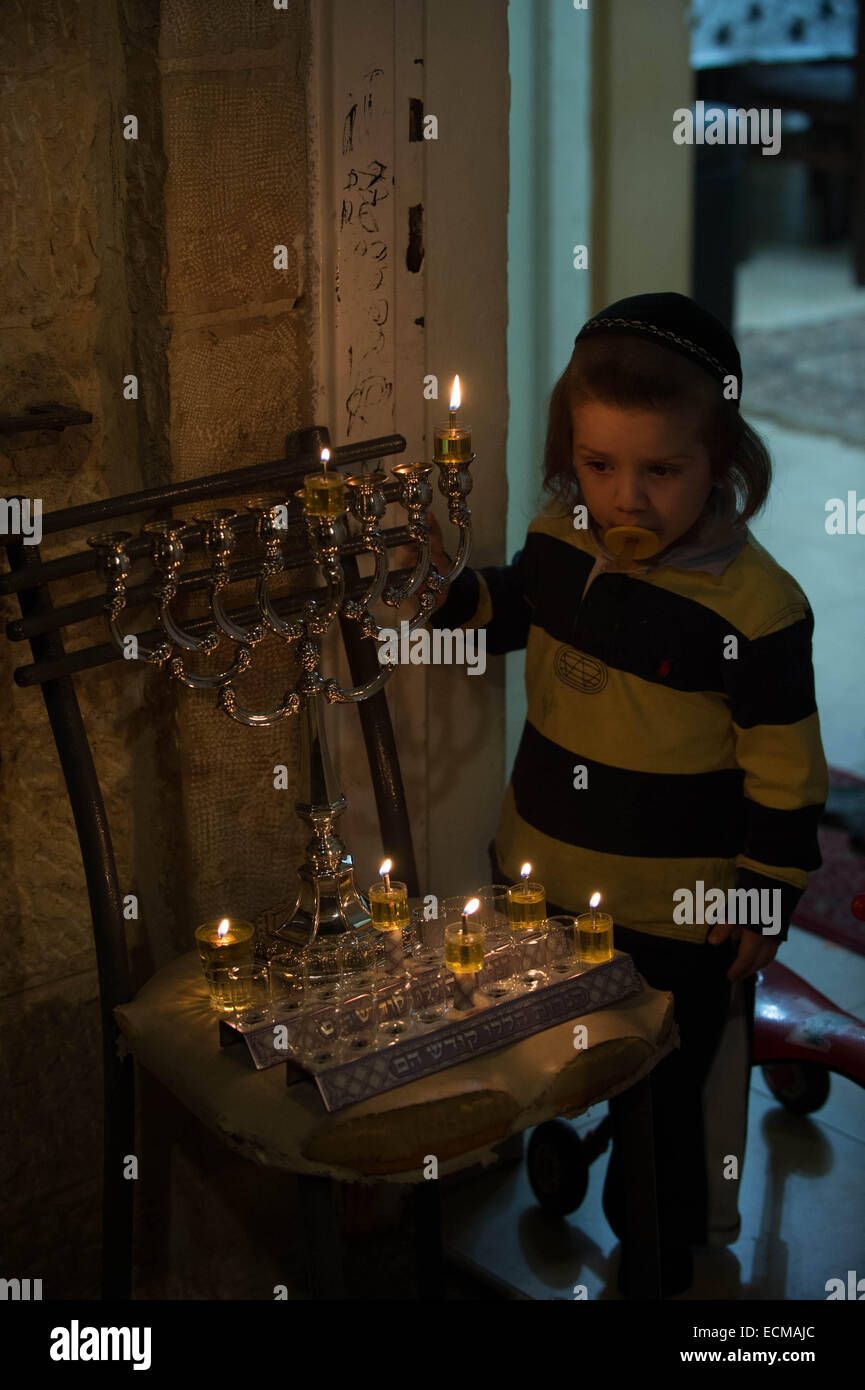 (141217) -- JERUSALEM, Dec. 17, 2014 (Xinhua) -- An Ultra-Orthodox Jewish boy watches a lit Hannukiya at his home to mark Hanukkah in the Old City of Jerusalem, on Dec. 16, 2014. Hanukkah, also known as the Festival of Lights and Feast of Dedication, is an eight-day Jewish holiday commemorating the rededication of the Holy Temple (the Second Temple) in Jerusalem at the time of the Maccabean Revolt against the Seleucid Empire of the 2nd Century B.C. Hanukkah is observed for eight nights and days, starting on the 25th day of Kislev according to the Hebrew calendar, which may occur at any time fr Stock Photo