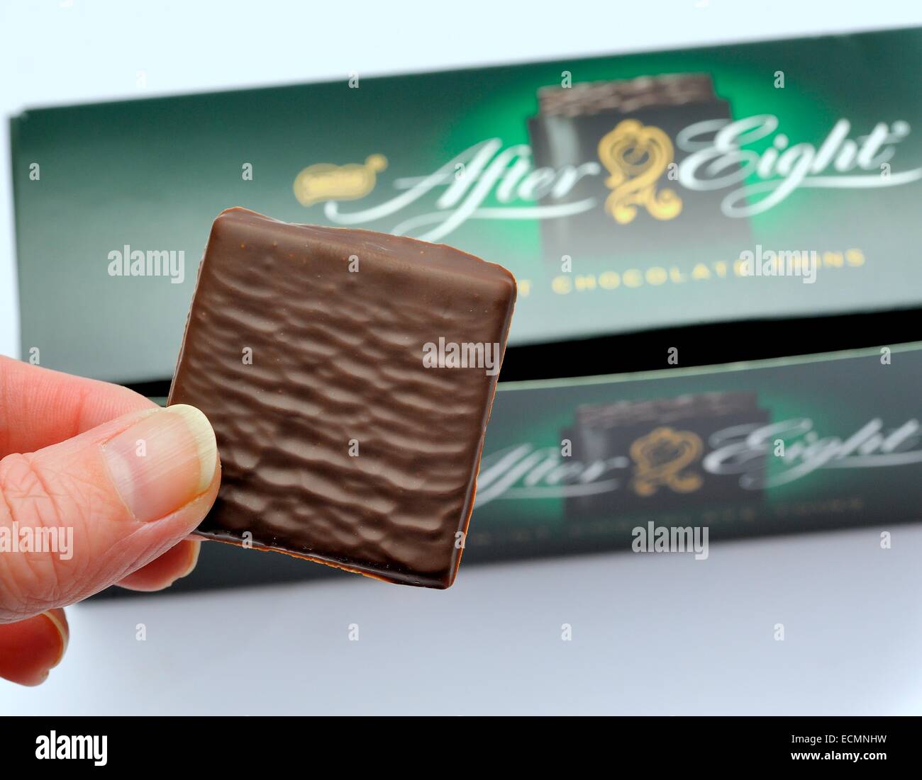 An After eight chocolate mint being held above the out of focus box