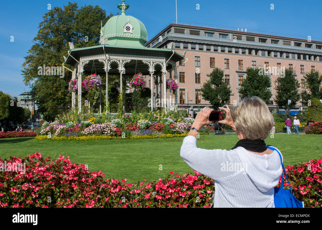 Bergen Norway music Pavillion colorful gazebo with flowers with woman tourist taking cell phone photo in downtown Stock Photo