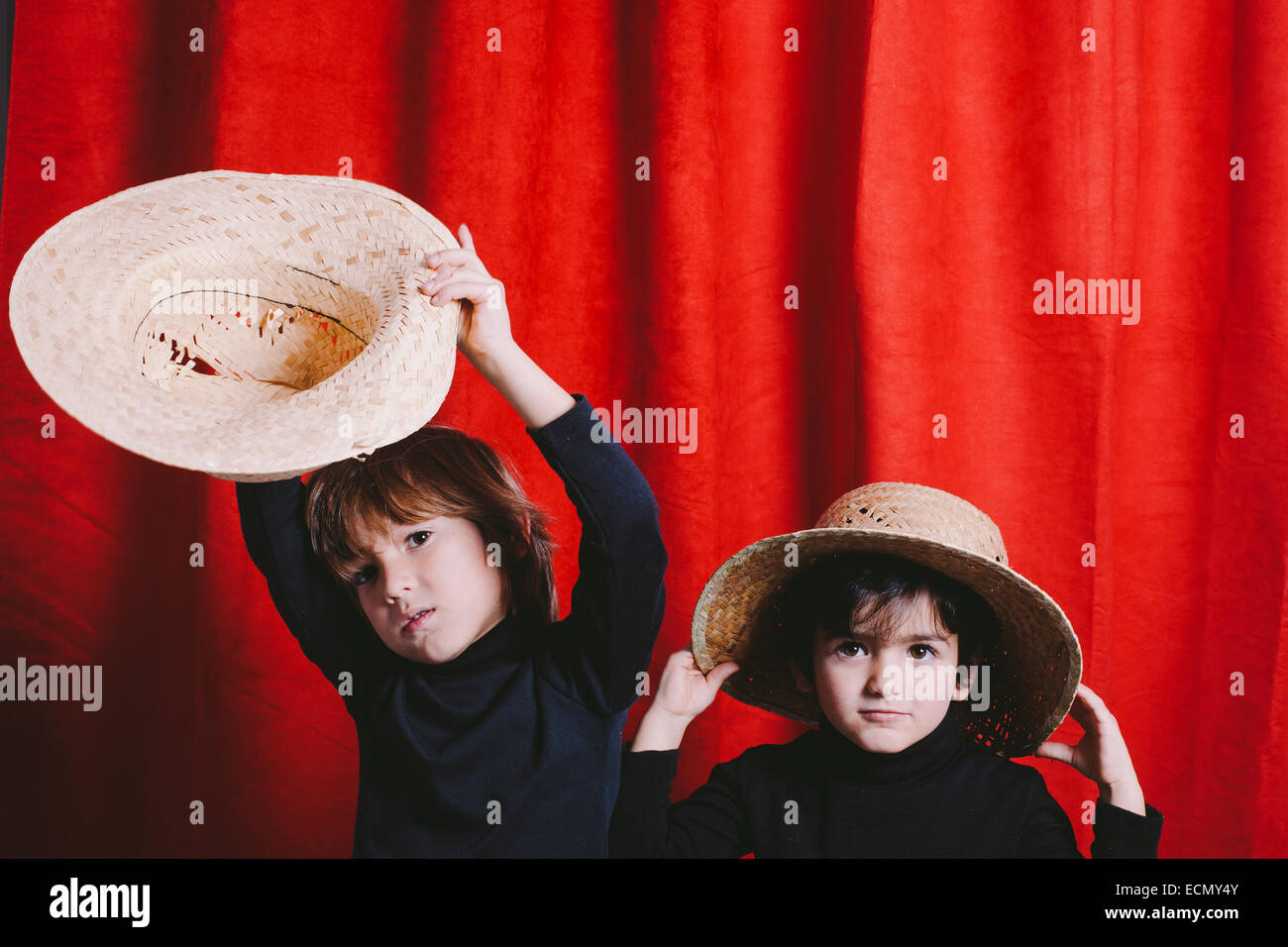 Studio portrait of two boys wearing black clothes and a straw hat Stock Photo