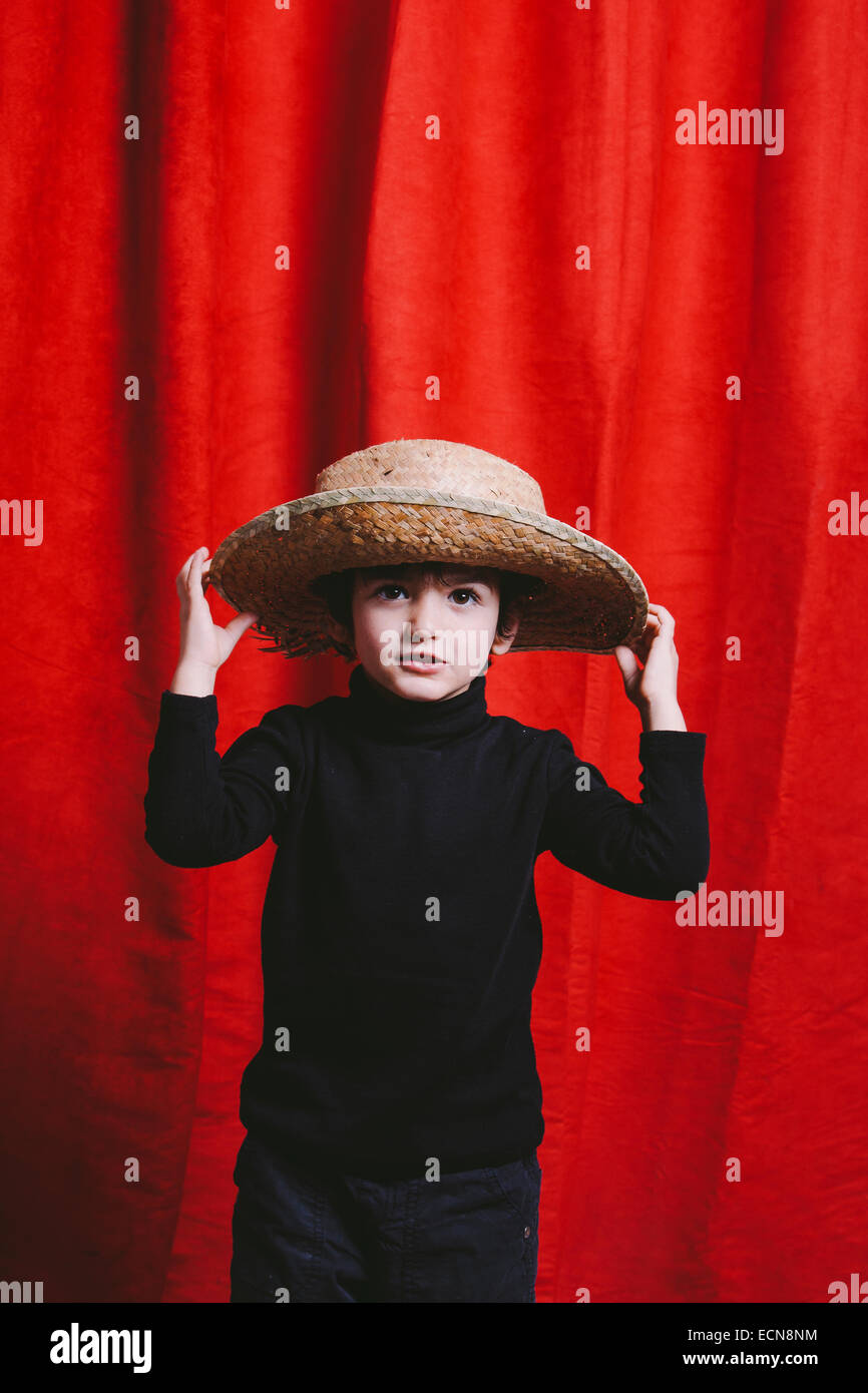 Studio portrait of three year old boy wearing black clothes and a straw hat Stock Photo