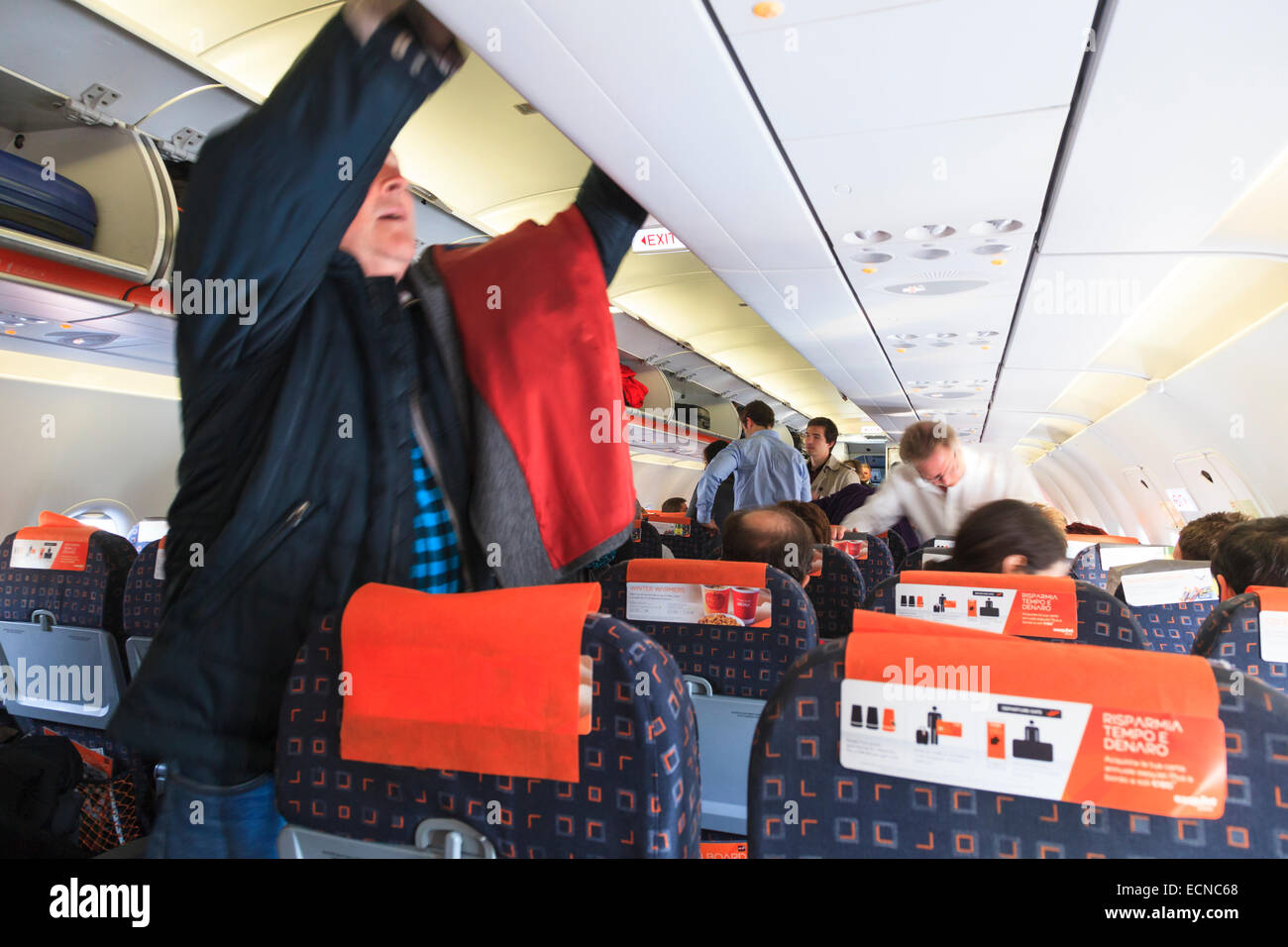 Passengers placing baggage into overhead lockers of Easyjet aircraft Stock Photo