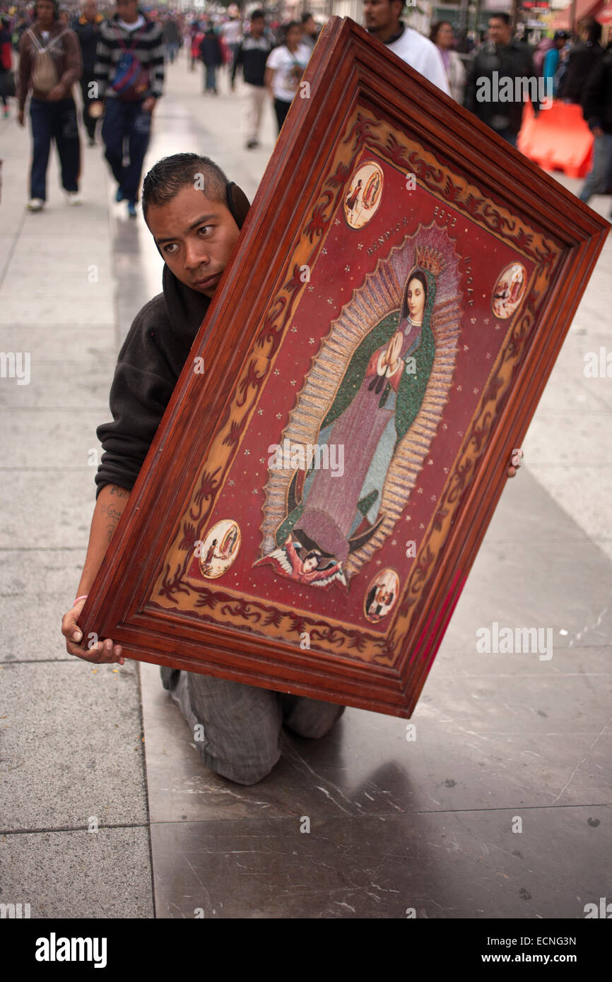 A pilgrim walks on his knees carrying an image of the Virgin of Guadalupe during the pilgrimage to the Basilica of Our Guadalupe Stock Photo