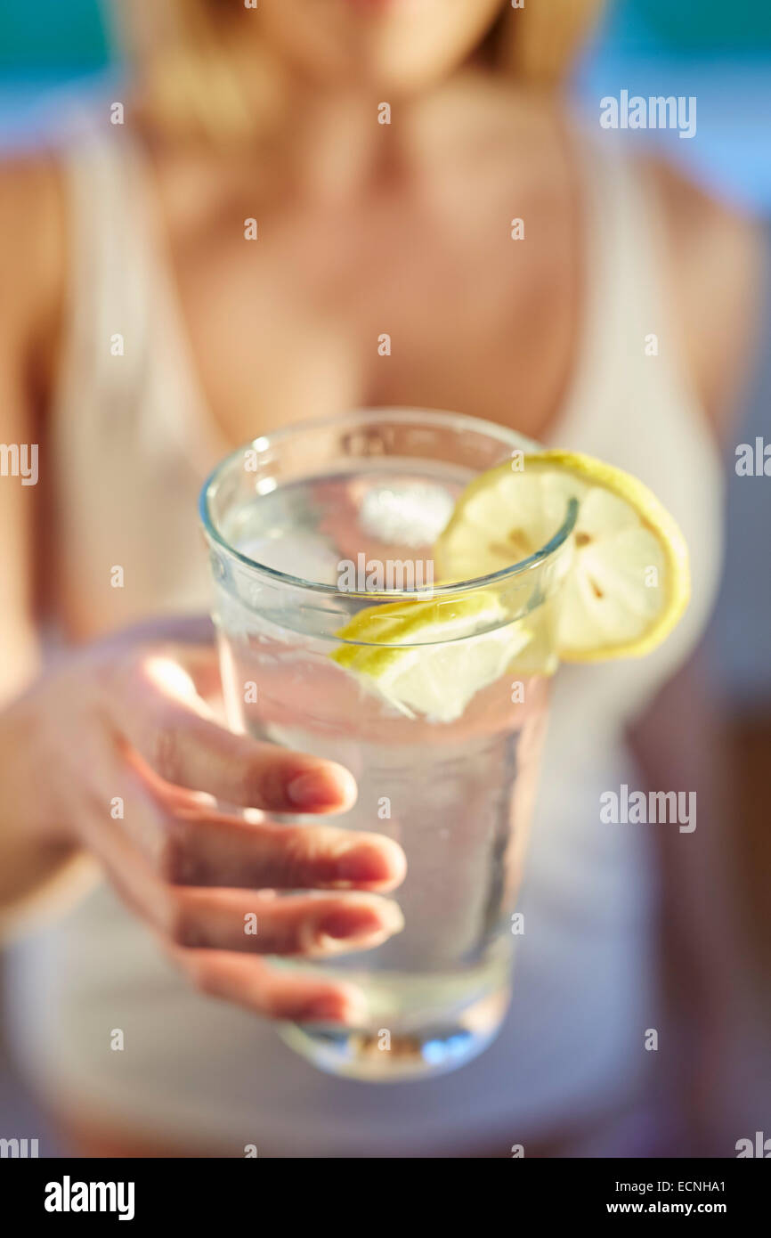 Girl drinking glass of iced water with Lemon Stock Photo