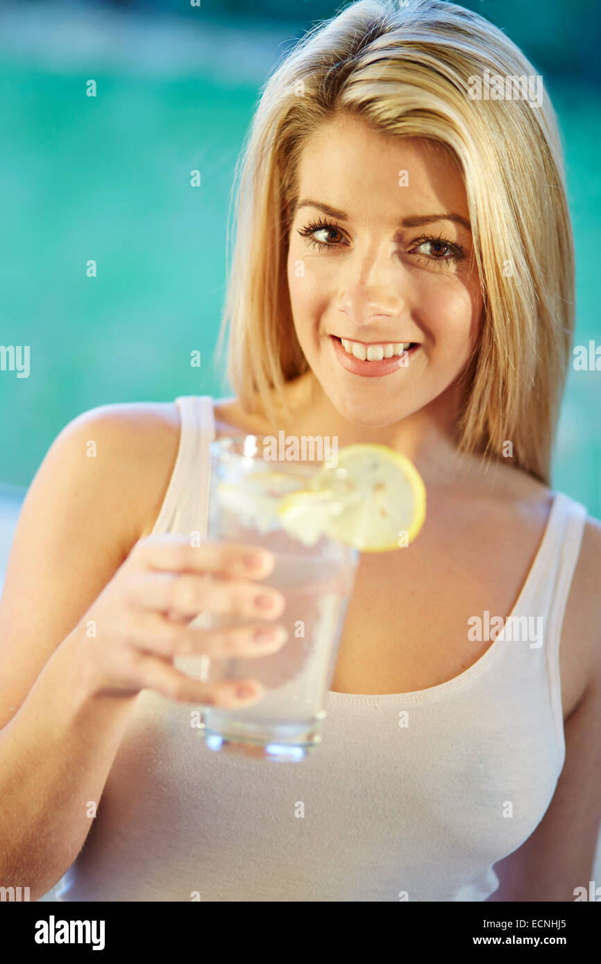 Girl drinking glass of iced water with Lemon Stock Photo