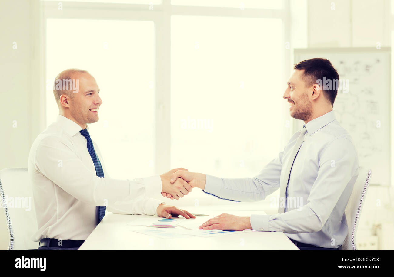 two smiling businessmen shaking hands in office Stock Photo - Alamy