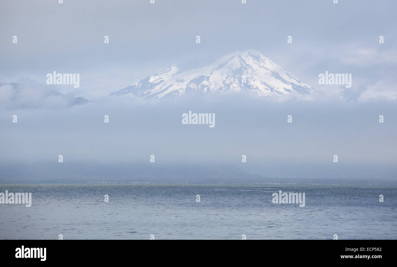 Mt. Augustine volcano peaks through the clouds on the Cook Inlet at Lake Clark National Park, Alaska Stock Photo