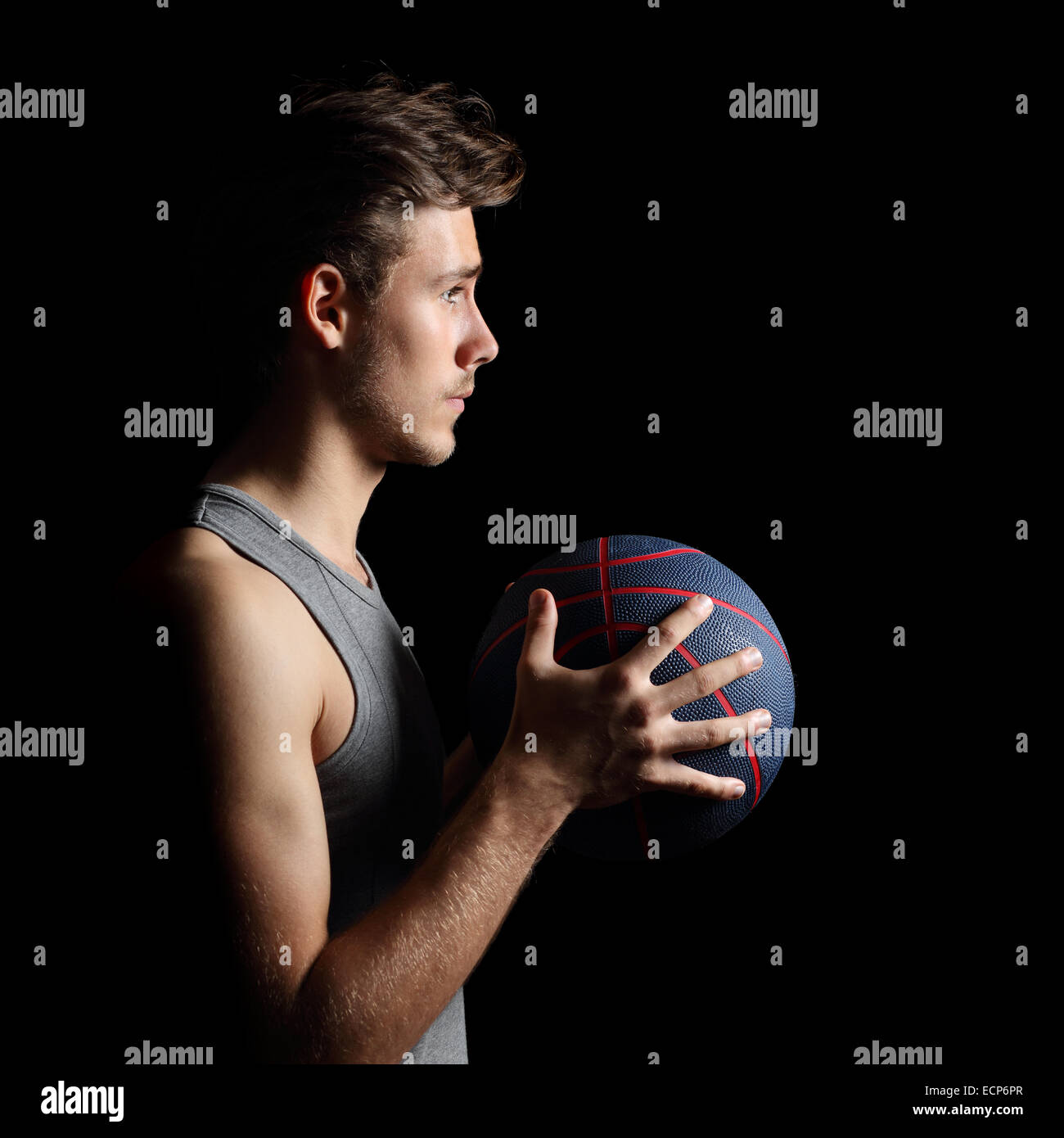 Side view of a basketball player holding a basket ball isolated on a black background Stock Photo