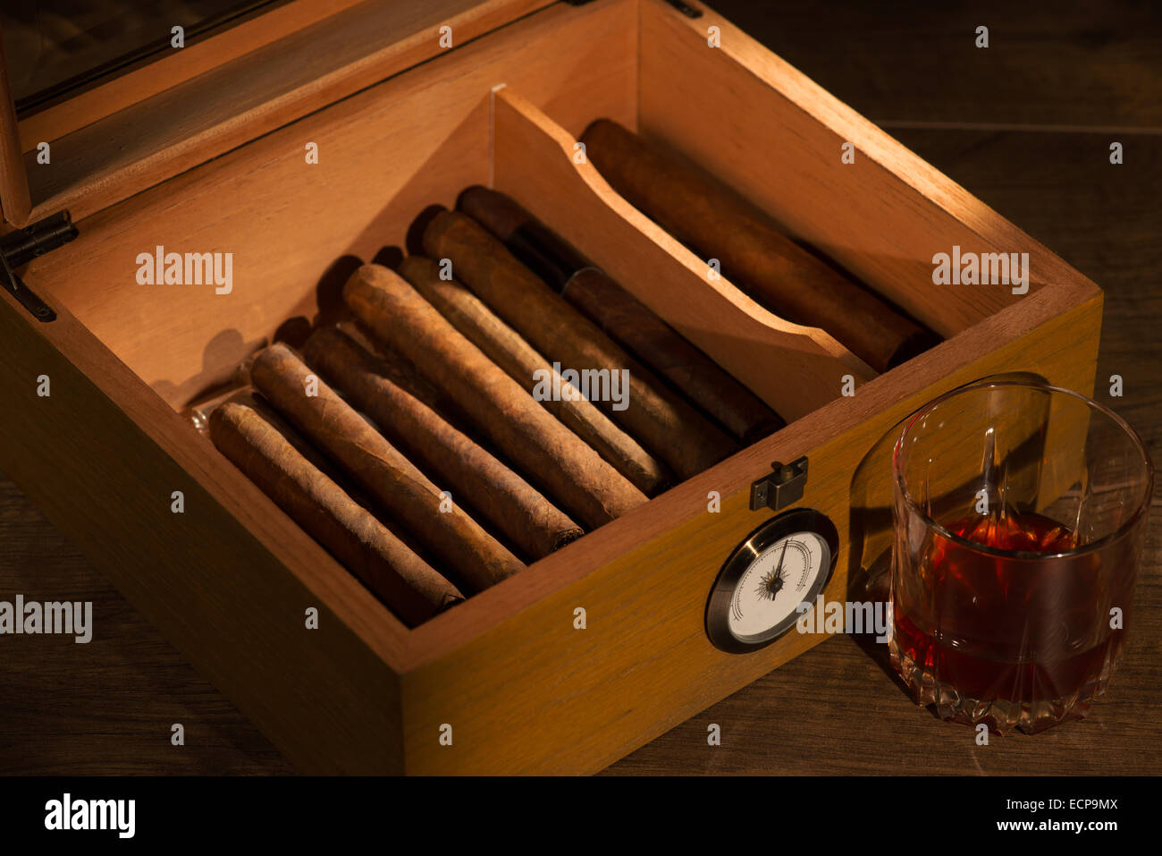 Selective focus on the great vintage humidor with Cuban cigars with glass of whiskey near it Stock Photo