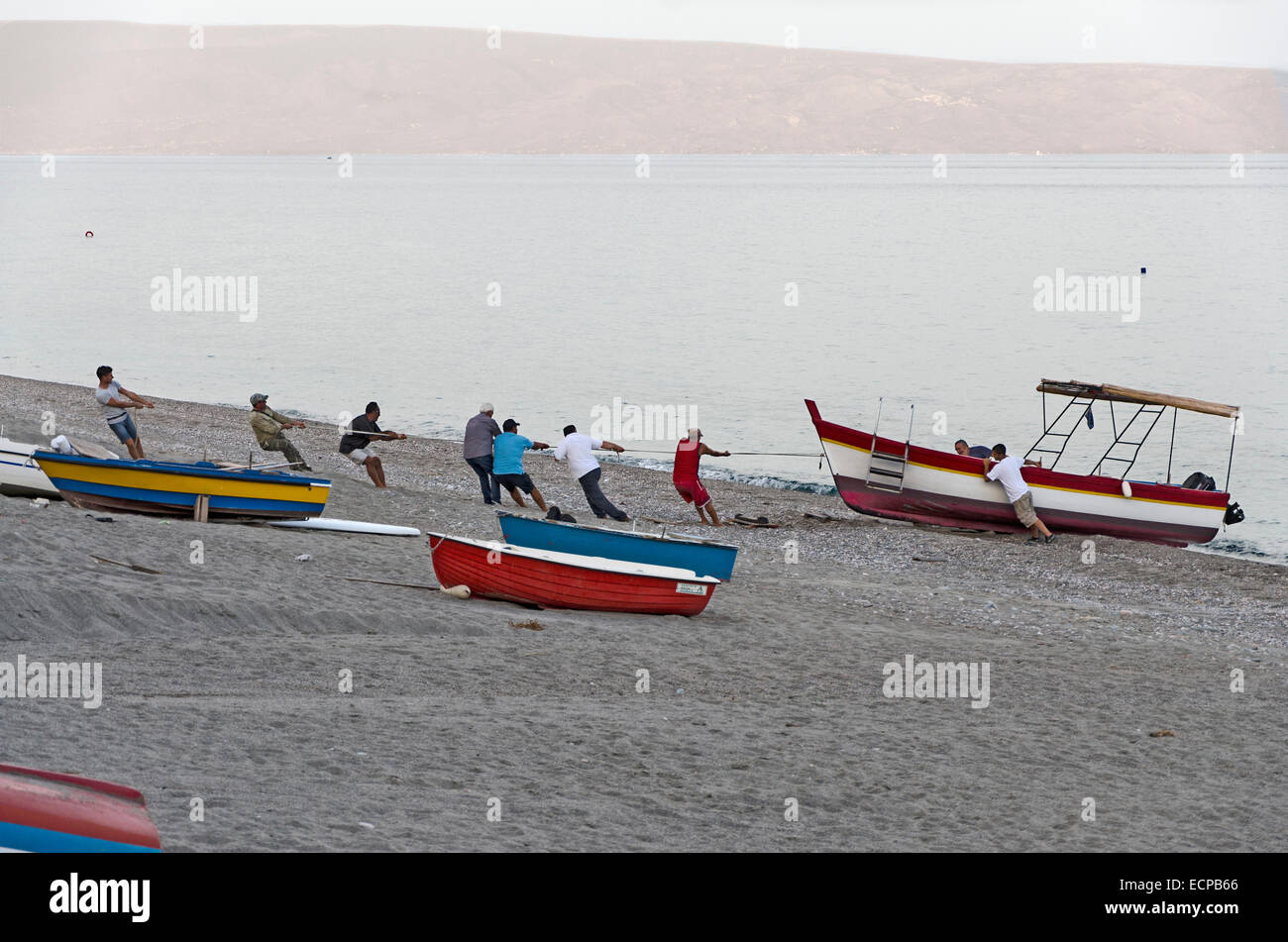 Letojanni, Sicily, Italy - September 26, 2012: Fishermen pulling fishing boat out from sea to start selling their caught fish at Stock Photo